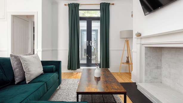 Een moderne woonkamer met een groene bank, een houten salontafel en een open haard.