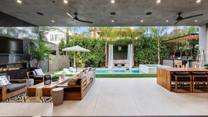 An outdoor living area with a pool, seating, and a barbecue setup. - Genesee Modern - Luxe Los Angeles Home | West Hollywood | Pool+Spa (Los Angeles)
