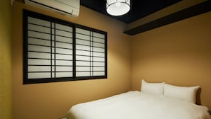 Een hotelkamer met een bed, een raam met een rasterpatroon en een plafondlamp.