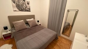 Un dormitorio con cama, mesitas de noche, un espejo y una obra de arte en la pared.