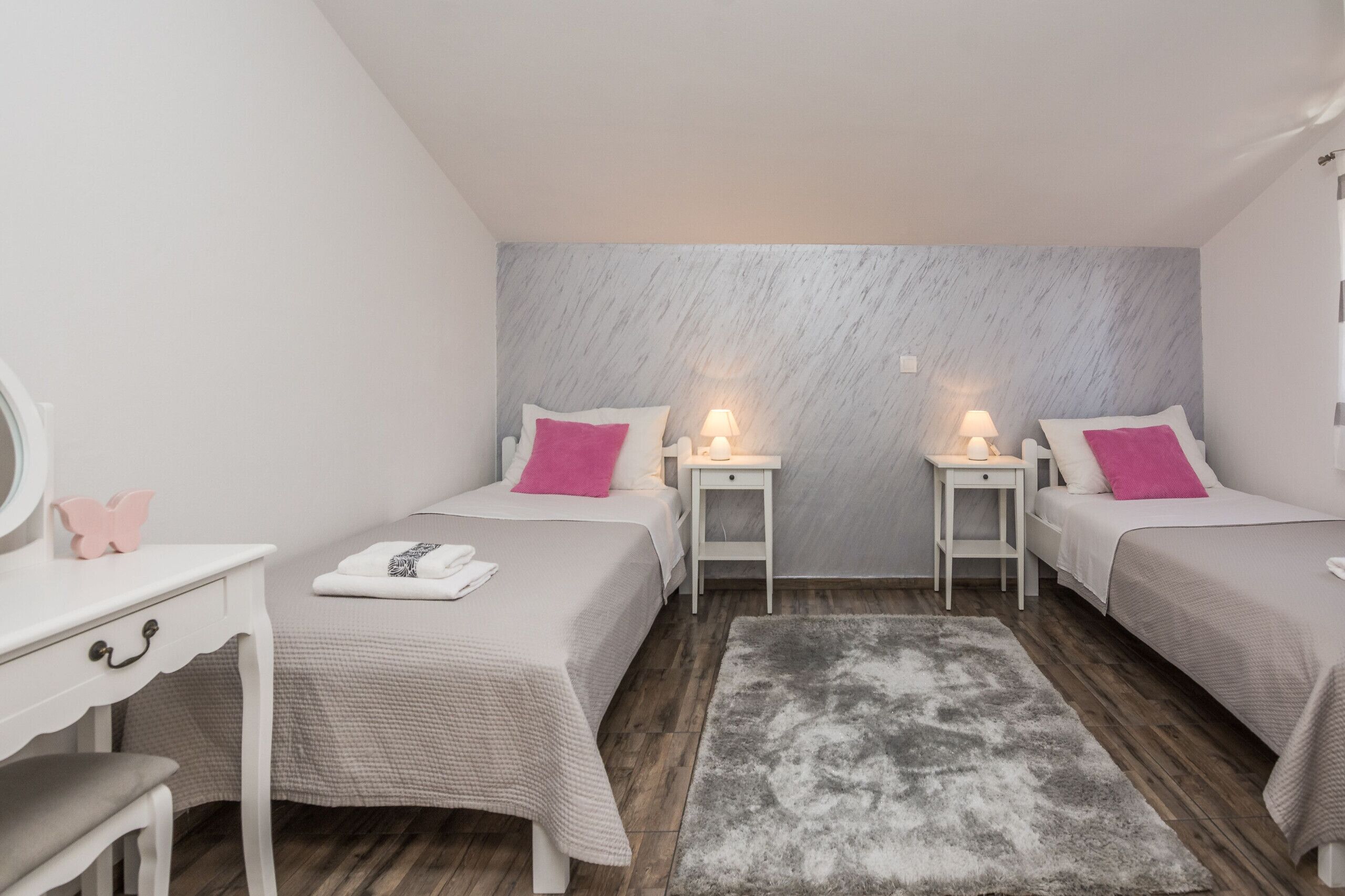A bedroom with two beds, a desk, and a mirror.