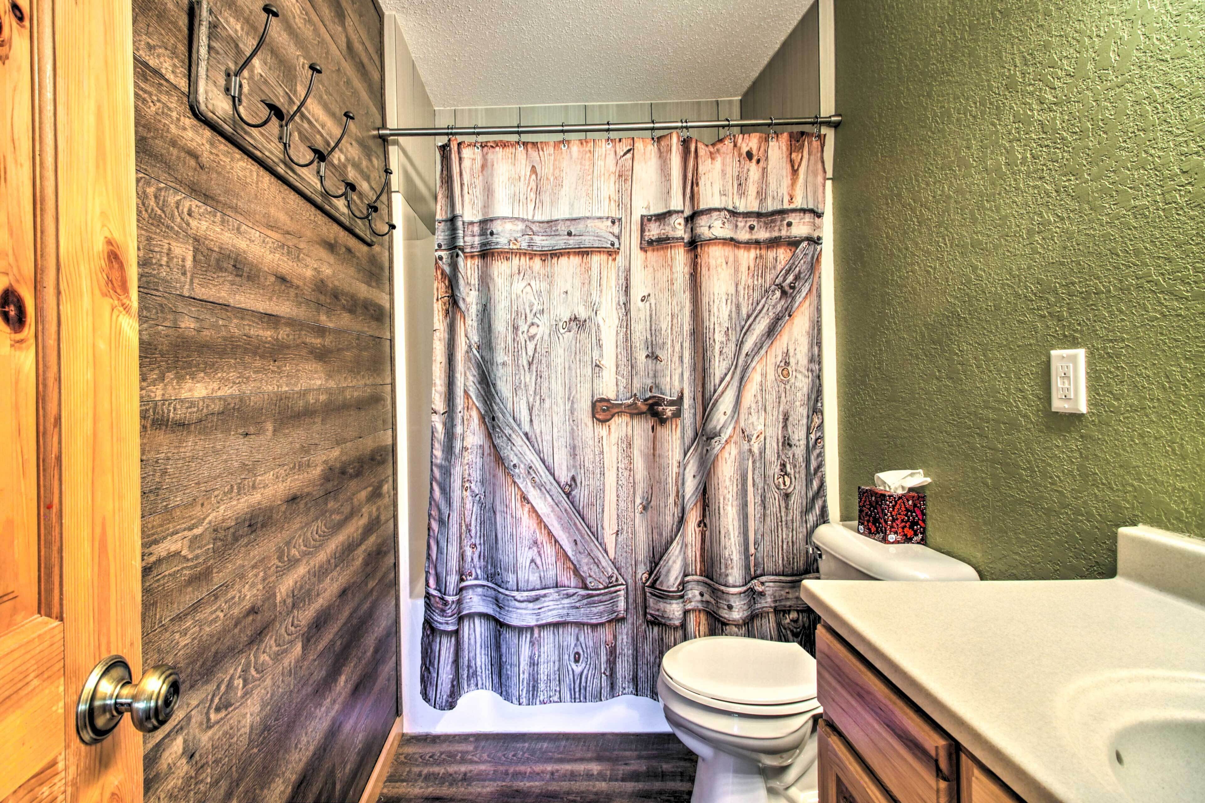 Een badkamer met een rustieke houten deur, een douchegordijn met een houtstructuur, een toilet en een wastafel.