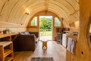 Un interior acogedor de madera con un sofá, un taburete pequeño y una zona de cocina.