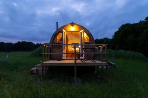 Una cabaña de madera con balcón, rodeada de hierba.