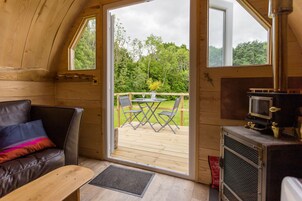 Interior acogedor de una cabaña con terraza de madera, un sofá y chimenea.