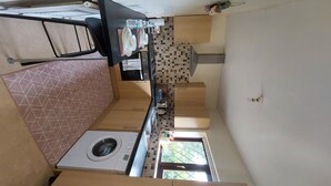 Eine kleine Küche mit Waschmaschine, kleinem Fenster und gefliestem Fliesenspiegel.