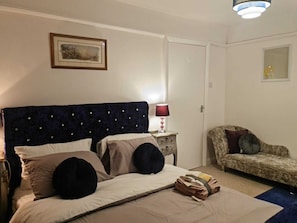A bedroom with a bed, a nightstand, a lamp, a chair, and a framed picture on the wall. - Immaculate 3-bed House in Middleton (Leeds)