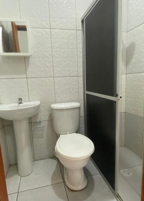 Casa de banho pequena com lavatório branco, sanita e cabine de duche.