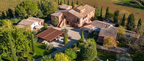 A large villa with a swimming pool, surrounded by lush gardens and vineyards.