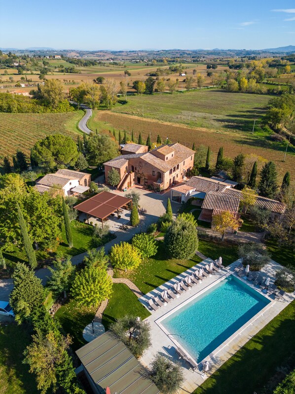A large villa with a swimming pool, surrounded by lush gardens and vineyards.