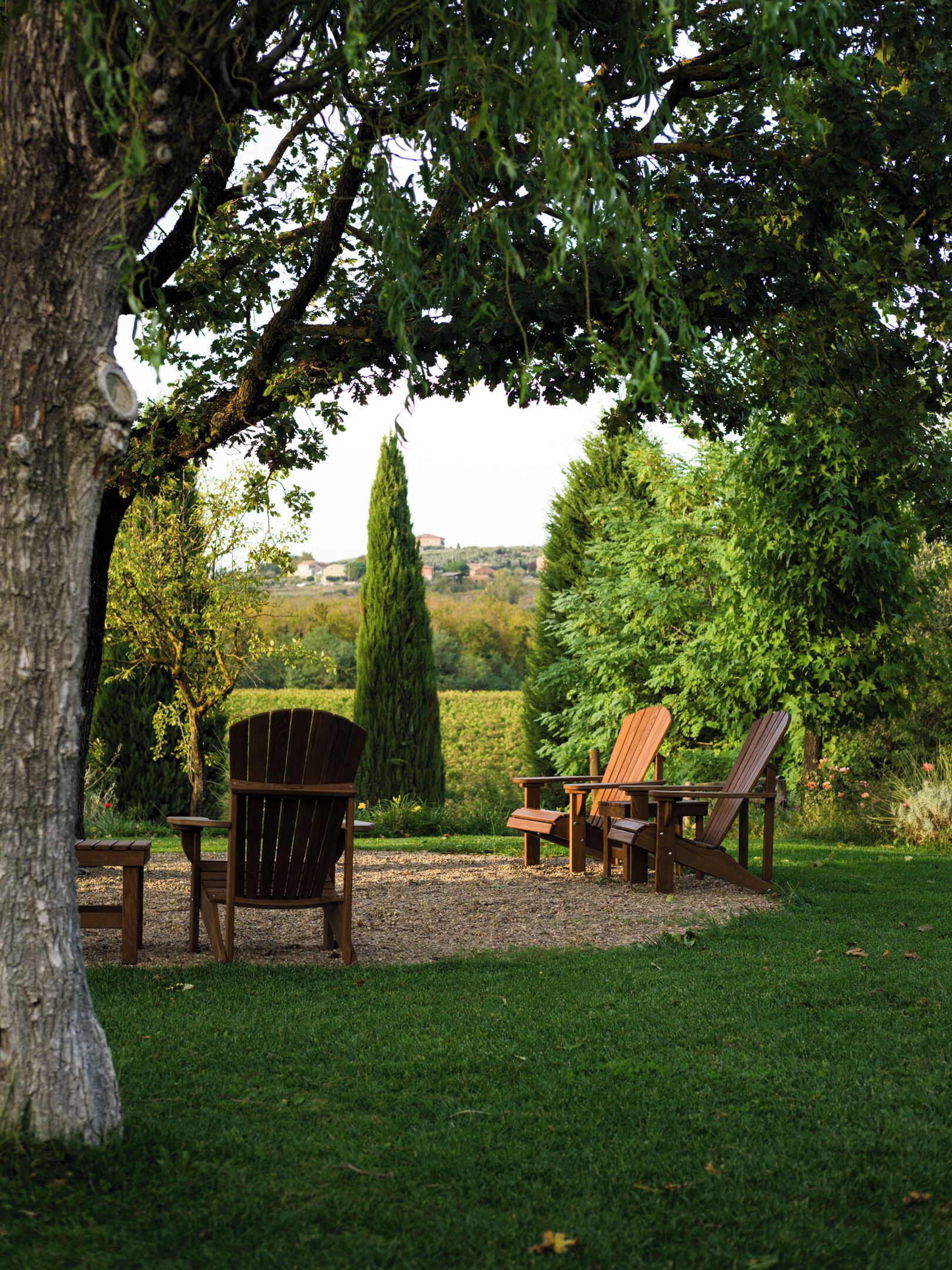 Un gazebo con due poltrone Adirondack e un tavolino, immerso nel verde e con vista su un paesaggio lontano.