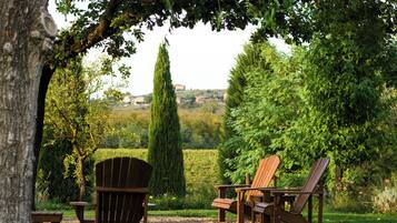 Un gazebo con due poltrone Adirondack e un tavolino, immerso nel verde e con vista su un paesaggio lontano.