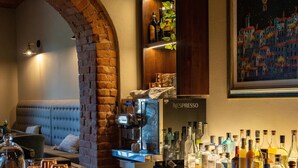Un coin bar agrémenté d’une arche en briques, d’une machine Nespresso, ainsi que de diverses bouteilles et verres disposés sur le comptoir.