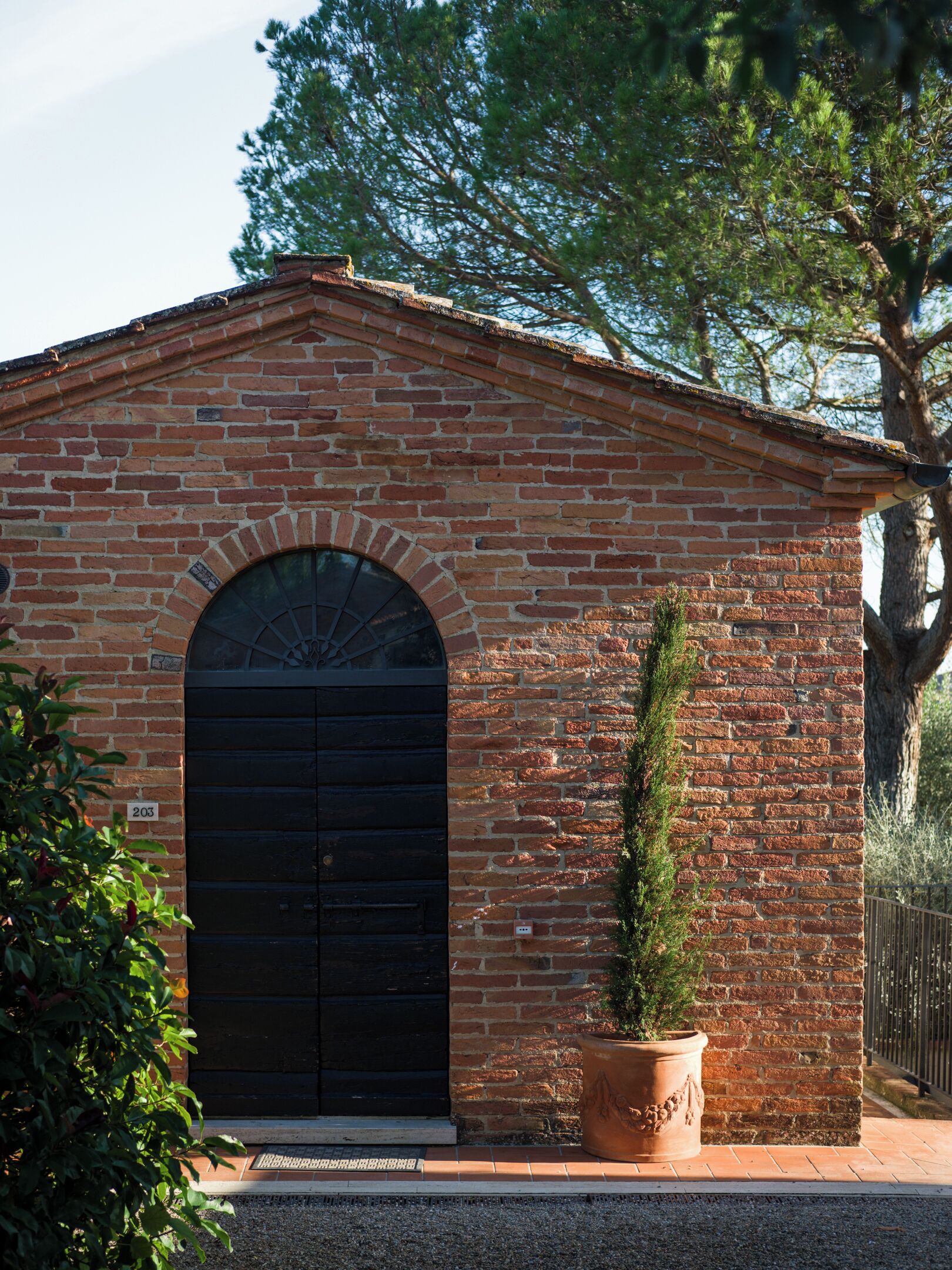 Un bâtiment en briques avec une porte noire et une petite plante en pot placée à côté.