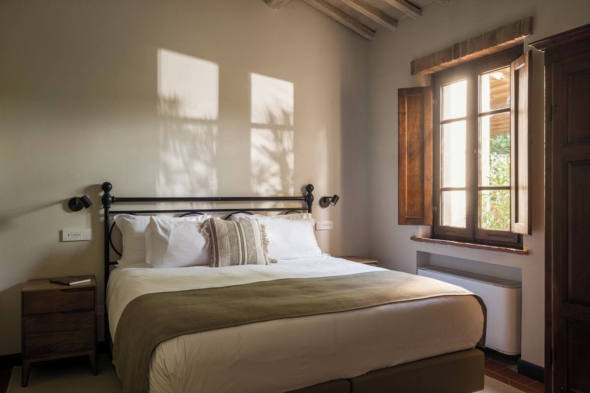 Ein Schlafzimmer mit einem Bett, Nachttischen, einem Fenster und einer Heizung.