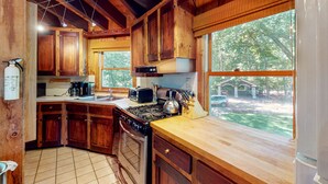 A wooden kitchen with a gas stove, oven, and various appliances. - Pet Friendly waterfront house on Lake Winnipesaukee sleeps 6 (Moultonborough)