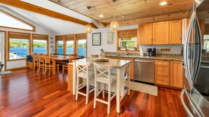 Una cocina moderna con armarios de madera, un refrigerador de acero inoxidable y una isla grande con taburetes de bar.