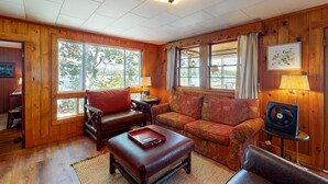 Une pièce chaleureuse avec des murs en bois, un canapé en cuir rouge, un divan à motifs floraux et un plancher en bois.