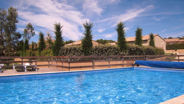 Ein Pool mit Holzterrasse, umgeben von Bäumen und Gebäuden.