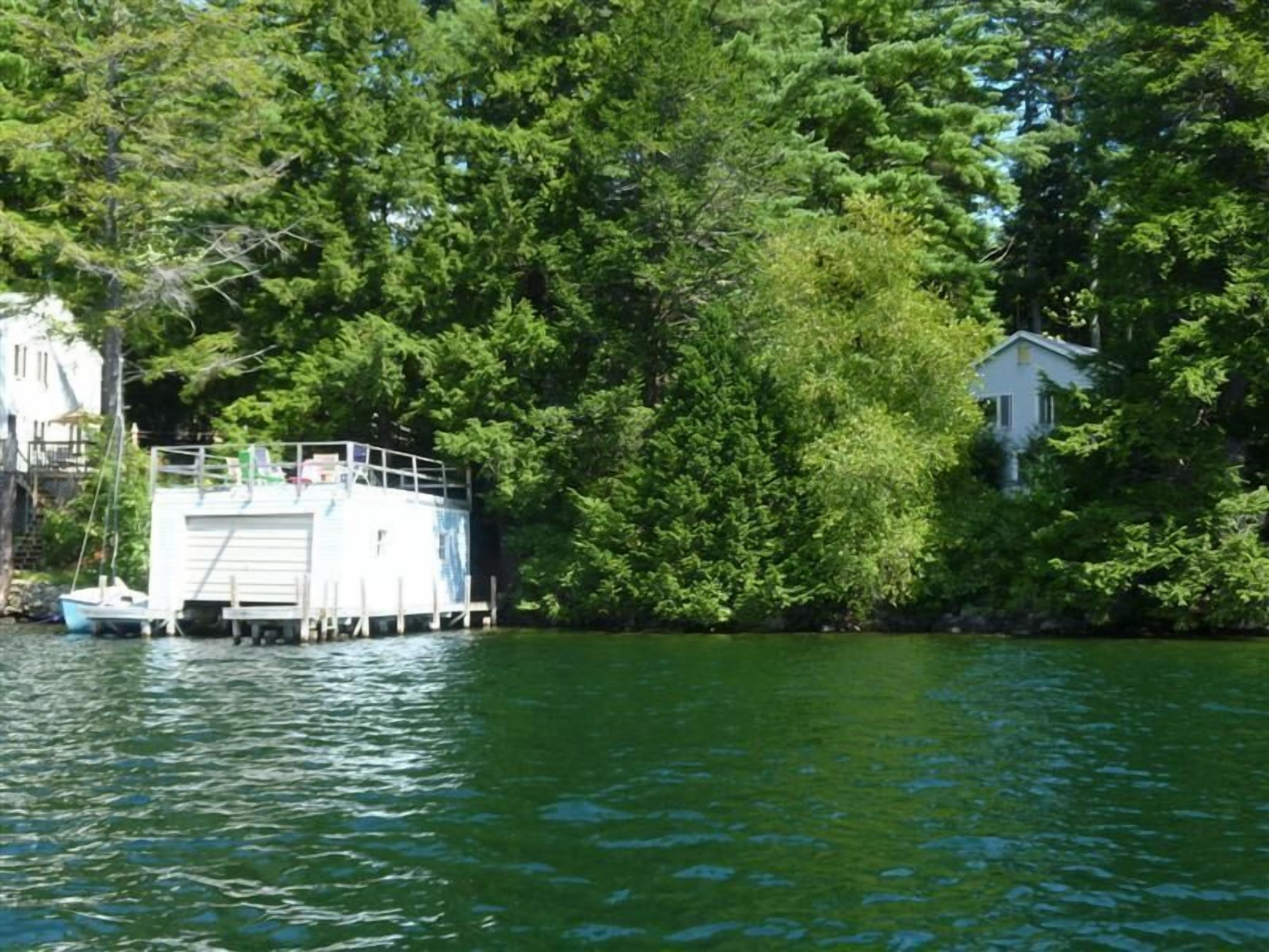 A docked boat on a calm lake surrounded by dense green trees.