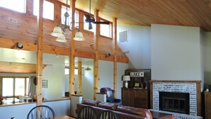 Uma sala de jantar com uma mesa e cadeiras de madeira, um sofá de couro e uma lareira com uma placa em cima.