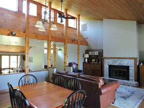 Relax in a spacious living area with a high ceiling, dining table, and cozy seating area featuring a fireplace.