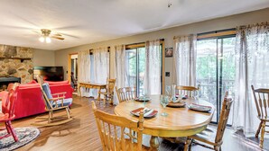 Ein geräumiges Wohnzimmer mit einem roten Sofa, Holzstühlen, einem Esstisch für sechs Personen und einem Steinkamin.