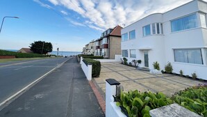 A residential street with houses, a clear sky, and a distant view of the sea. - The Emberton (Bridlington)