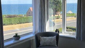 A room with a large window offering a view of the sea and a road. - The Emberton (Bridlington)