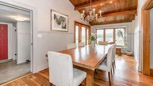 Un vaste espace dédié à la salle à manger, avec une table et des chaises en bois, un lustre et une grande fenêtre offrant une vue sur l’extérieur.