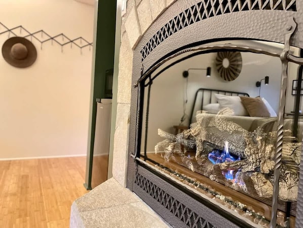 Une cheminée agrémentée d’un miroir décoratif, un chapeau accroché au mur et un lit à l’arrière-plan.