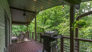 A covered outdoor deck with a grill, chairs, and a table. - The Sunset Chalet | Pet-friendly, Deck & 5 Minutes to Black Mountain! (Black Mountain)