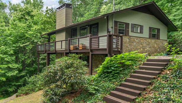 A two-story house with a stone foundation, a balcony, and a staircase leading to the entrance. - The Sunset Chalet | Pet-friendly, Deck & 5 Minutes to Black Mountain! (Black Mountain)