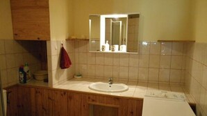 Une salle de bain avec un meuble-lavabo en bois, un lavabo blanc, un miroir au-dessus du lavabo et des toilettes.