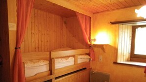 Une cabine avec des lits superposés, une fenêtre avec des rideaux et un luminaire fixé au mur.