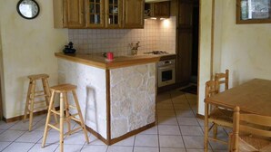 Une cuisine avec des meubles en bois, un îlot central doté de tabourets, une cuisinière et une table à manger avec des chaises.