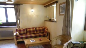 Un salon avec un canapé, un fauteuil en osier, une table basse et un tapis.