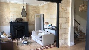 A living room with a fireplace, a sofa, a coffee table, and a staircase. - Belle Maison Bordelaise Avec Piscine ! (Bordeaux)