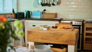A kitchen with a wooden countertop, a cutting board with bread and cheese, and a bowl of olives. - A Charming cottage in the Heart of Laugharne (Laugharne)