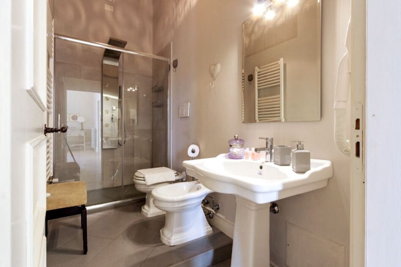 A bathroom with a glass-enclosed shower, a toilet, and a pedestal sink.