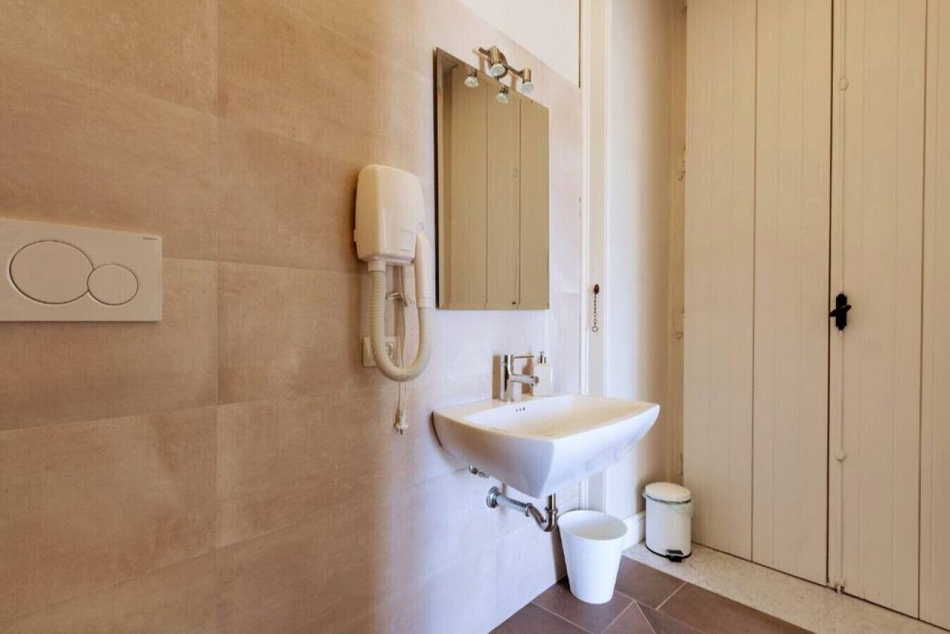 A bathroom with a white sink, a mirror, and a toilet.
