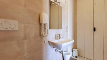 A bathroom with a white sink, a mirror, and a toilet.