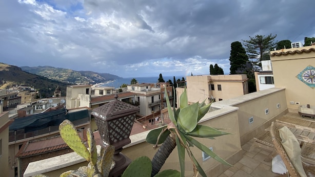 A rooftop terrace with a cactus plant, a decorative lantern, and a view of the cityscape and mountains in the background. - Villa Zecca, Taormina (Taormina)