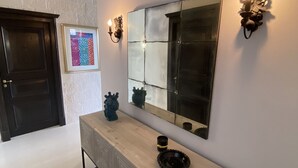 A hallway with a wooden console table, a large mirror, and wall sconces. - Villa Zecca, Taormina (Taormina)