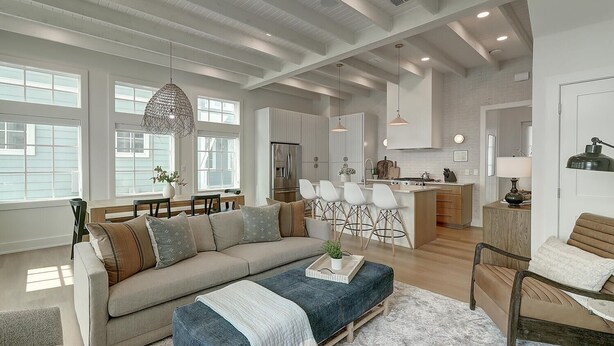 A spacious living room with a large sofa, a coffee table, and a dining area with chairs.