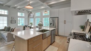 A modern kitchen with a large island, stainless steel appliances, and pendant lighting.