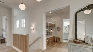 A spacious room with a wooden staircase, a bunk bed, and a large mirror.