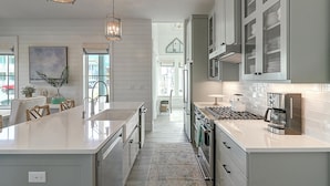 A modern kitchen with a large island, stainless steel appliances, and a view to the dining area.