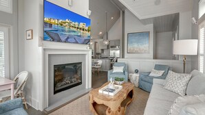 A modern living room with a fireplace, a large TV mounted above it, and a cozy seating area with a coffee table. - Grand Central 226 GR (Port Aransas)