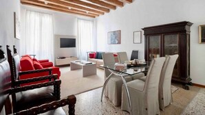 Una sala de estar con una mesa de centro de vidrio, un sofá rojo y sillas de madera.